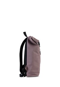 Vista lateral de una mochila minimalista en color malva con tirantes acolchados negros y un asa en la parte superior, sobre un fondo blanco.