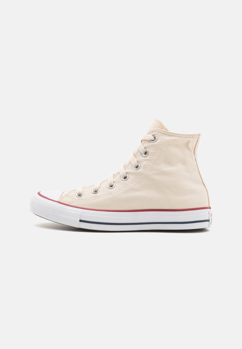 Basket montante en toile beige avec semelle en caoutchouc blanche, rayures rouges et noires, et lacets blancs sur un fond uni.