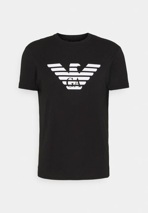 Svart bomull T-skjorte med en hvit ørn-logo laget av horisontale striper med "GA" i midten. Kortermet og rund halsdesign.