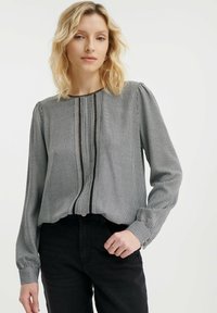 Zwart-wit geblokte blouse met een ronde halslijn, gefronste schouders en dunne naden. Gestyled met zwarte hoge taille jeans.