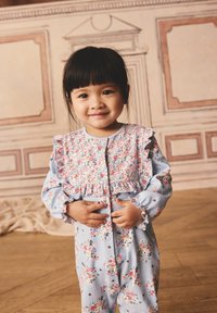 Laste kombekas helesinisel lillemustril, volangiliste õlgade, pikkade varrukate ja nööpidega sulguriga. Pehme kangas peente detailidega.