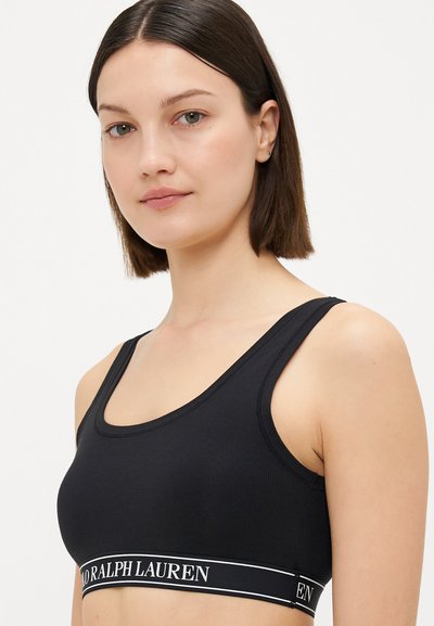 Black ribbed sports bra with a wide elastic band featuring white "Ralph Lauren" logo, scoop neckline, and wide shoulder straps.