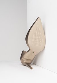 Chaussure à talons hauts en bronze avec un bout pointu et un dessus lisse et brillant. Présente une semelle texturée et un talon aiguille fin. Taille 37.