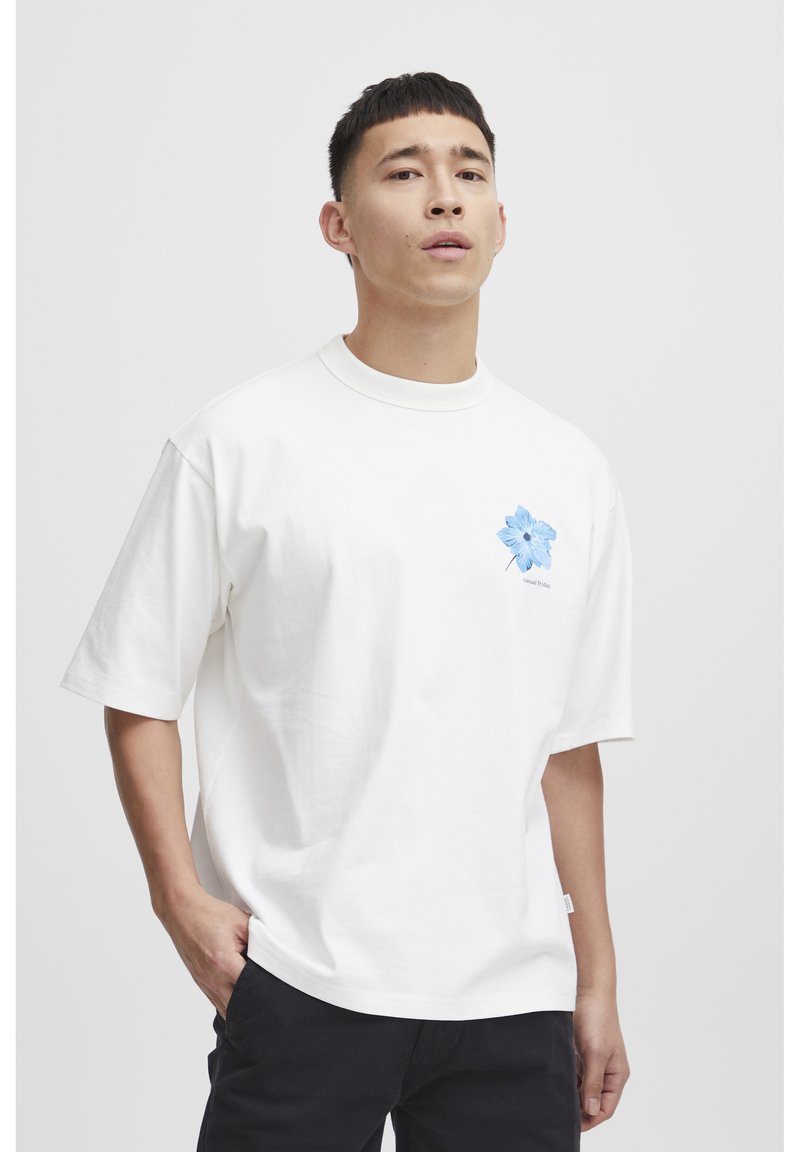 Hvid bomulds T-shirt med korte ærmer, med et blåt blomstermotiv på venstre side og rund halsudskæring. Enkel design, afslappet pasform.