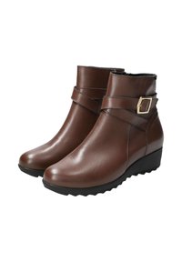 Bottines en cuir marron avec une boucle sur le côté, texture lisse, bout rond et talon en forme de coin avec une semelle robuste pour une meilleure adhérence.