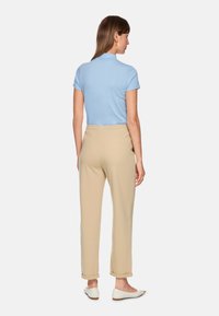 Light blue short-sleeve polo shirt paired with beige elastic waist pants, featuring a relaxed fit and rolled cuffs.
