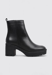 Bottine en cuir noir avec un bout arrondi, un talon épais strié, et une languette à l'arrière. Texture lisse avec peu de détails.