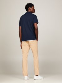 Polo de color navy combinado con chinos color caqui. El conjunto se complementa con zapatillas blancas, enfatizando un diseño limpio y minimalista.