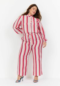 Set de două piese cu dungi verticale roșii, albe și albastre, compus dintr-o cămașă cu guler și pantaloni largi. Textură de țesătură netedă.
