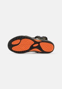 Black and orange athletic shoe sole with a textured rubber surface. Features a distinct orange grip pattern in a wavy design.