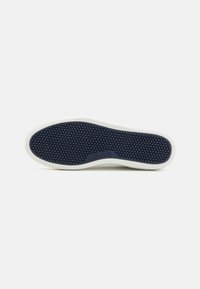 Semelle de chaussure avec motif de bande de roulement hexagonal bleu foncé et bordure blanche, avec logo Levi's embossé au centre.