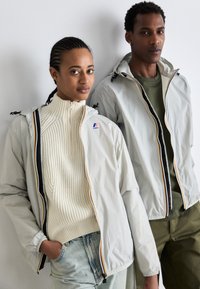 Lightweight, zippered jackets in pale gray with colored accents; paired with a cream ribbed turtleneck and green top. Casual denim and pants.