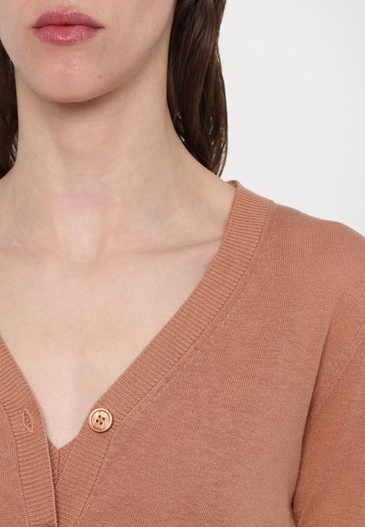Cardigan roz prăfuit cu decolteu în V, textură ribbed și un detaliu proeminent cu nasture în zona pieptului. Material moale, tricotat.