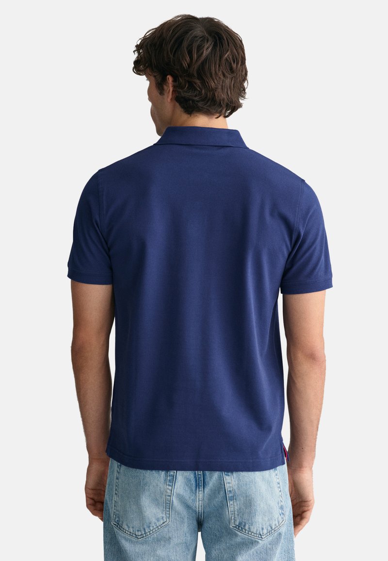 Marineblaue Poloshirt aus glattem Stoff, mit kurzen Ärmeln und traditionellem Kragen. Ausgestattet mit einem kleinen Logodetail am Saum.