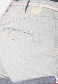 Svetle šedé džíny kraťasy s pleteným páskem, zadními kapsami na knoflík a jemnou texturou, končící těsně nad polovinou stehna.