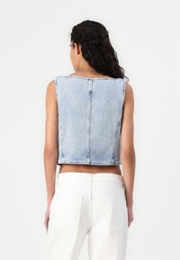 Abgeschnittene Jean-Weste in Hellblau mit ärmellosem Design. Verfügt über einen geraden Rückensaum, sichtbare Nähte und eine leicht ausgewaschene Textur.