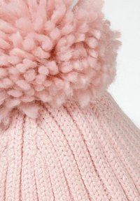 Strikket lyserød hue med en fluffy pompon på toppen. Har ribbet tekstur og blødt garn, der giver varme og komfort.