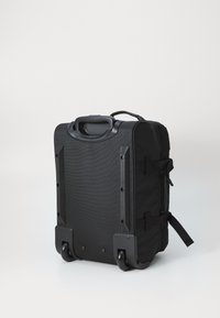 Black rolling suitcase made of textured fabric, featuring a top handle, two wheels, side straps, and a smooth, flat base for stability.