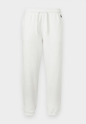 Pantalon de survêtement en polaire blanche avec taille élastique, cordons de serrage, poignets élastiques, et petit logo noir près de la hanche sur fond uni.