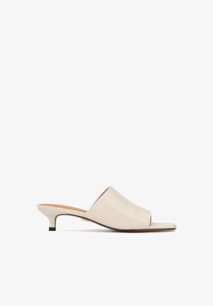 Sandali scivolati in pelle beige con punta aperta, tacco basso, texture liscia e design minimalista. Presentano una finitura leggermente lucida.