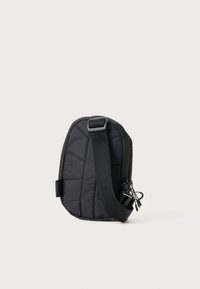 Borsa a tracolla nera imbottita con una forma ovale elegante, cinturino regolabile, chiusura con zip e una sottile texture trapuntata.