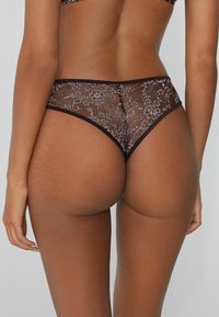 Kanten bikini in donkerpaars met doorzichtige bloempatronen. Kenmerkt zich door een hoge uitsnijding en een soepele tailleband voor een comfortabele pasvorm.