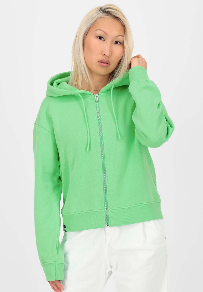 Sweat à capuche vert zippé, coupe ample, avec des poignets côtelés. Fabriqué en tissu doux, avec une fermeture éclair à l'avant et des poches latérales.