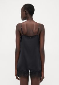Svart sateng-camisole med blonderkant, med tynne justerbare stropper og knappedetaljer bak. Glatt tekstur og løs passform.