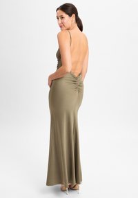 Oliven grüne, figurbetonte Maxi-Kleid mit Spaghettiträgern und tiefem Rücken. Verfügt über geraffte Details hinten. Seidige Textur, bodenlang.