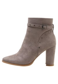 Šedá semišová členková bota s špičatou špičkou, silným vysokým podpatkem a ozdobným páskem se stříbrnými cvočky a přezkou na straně.