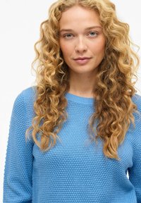 Jasnoniebieski sweter z fakturowanym wzorem dzianiny, okrągłym dekoltem i długimi rękawami. Materiał wydaje się miękki i wygodny.