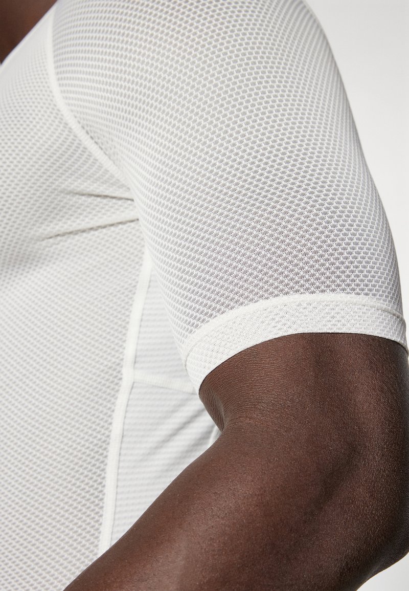 T-shirt de sport à manches courtes en tissu en maille blanche, doté d'un motif hexagonal, d'une texture lisse et d'arêtes douces sur les manches.