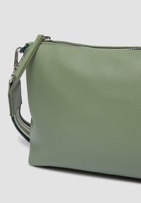 Borsa verde in pelle con finitura testurizzata, dotata di chiusura a zip e manico in tessuto con un motivo intrecciato a contrasto.