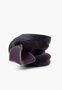 Zapato de terciopelo púrpura con un diseño de parte superior rizada y suela de goma negra. Presenta una textura suave, creando una forma y apariencia únicas.