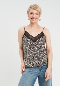Leopardenmuster-Camisole mit V-Ausschnitt und schwarzem Spitzenbesatz; verstellbare Spaghetti-Träger; leichtes Material; getragen mit blauen Jeans.