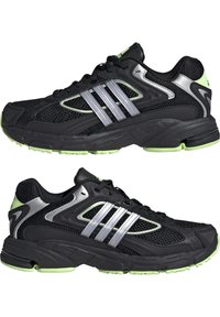 Svarta nätatletikskor med silveraccenter och tre ränder. Har en grön sula och detaljer, dämpad design och strukturerad ovandel.