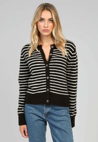 Cardigan rayé noir et blanc avec un col en V, des boutons sur le devant et un ourlet côtelé ; fabriqué dans un matériau doux avec des manches longues et des bords arrondis.