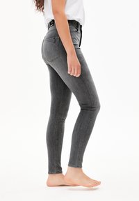 Vaqueros gris claro de corte slim, de cintura alta, fabricados en denim, con bolsillos laterales, costuras en contraste y una textura suave.