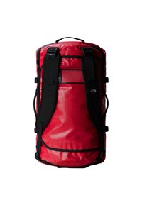 Rød duffelbag laget av slitesterkt materiale. Har svarte stropper, en mesh-lomme og en teksturert overflate med et sekskantet mønster.