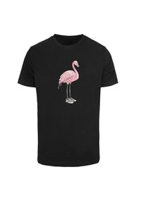 Juodas trumpas rankoves marškinėliai su rožiniu flamingo grafiku, avinčiu baltus sportbačius. Marškiniai turi klasikinį apvalų kaklą.