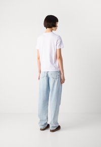 Hvit bomull t-skjorte med korte ermer og rund hals, kombinert med lyseblå, løstsittende jeans og brune slip-on sko.