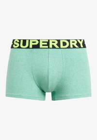 Miętowe bokserki wykonane z miękkiego materiału z czarnym elastycznym pasem, na którym znajduje się napis "SUPERDRY" w kolorze żółtym. Dopasowany krój.