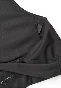 Svart BH laget av glatt stoff med sømløst design, med justerbare stropper og en diskret logo på båndet.