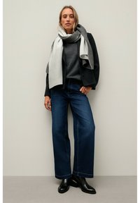 Wide-leg dark blue jeans paired with a charcoal gray sweater and a light gray striped scarf. Black ankle boots complete the outfit.