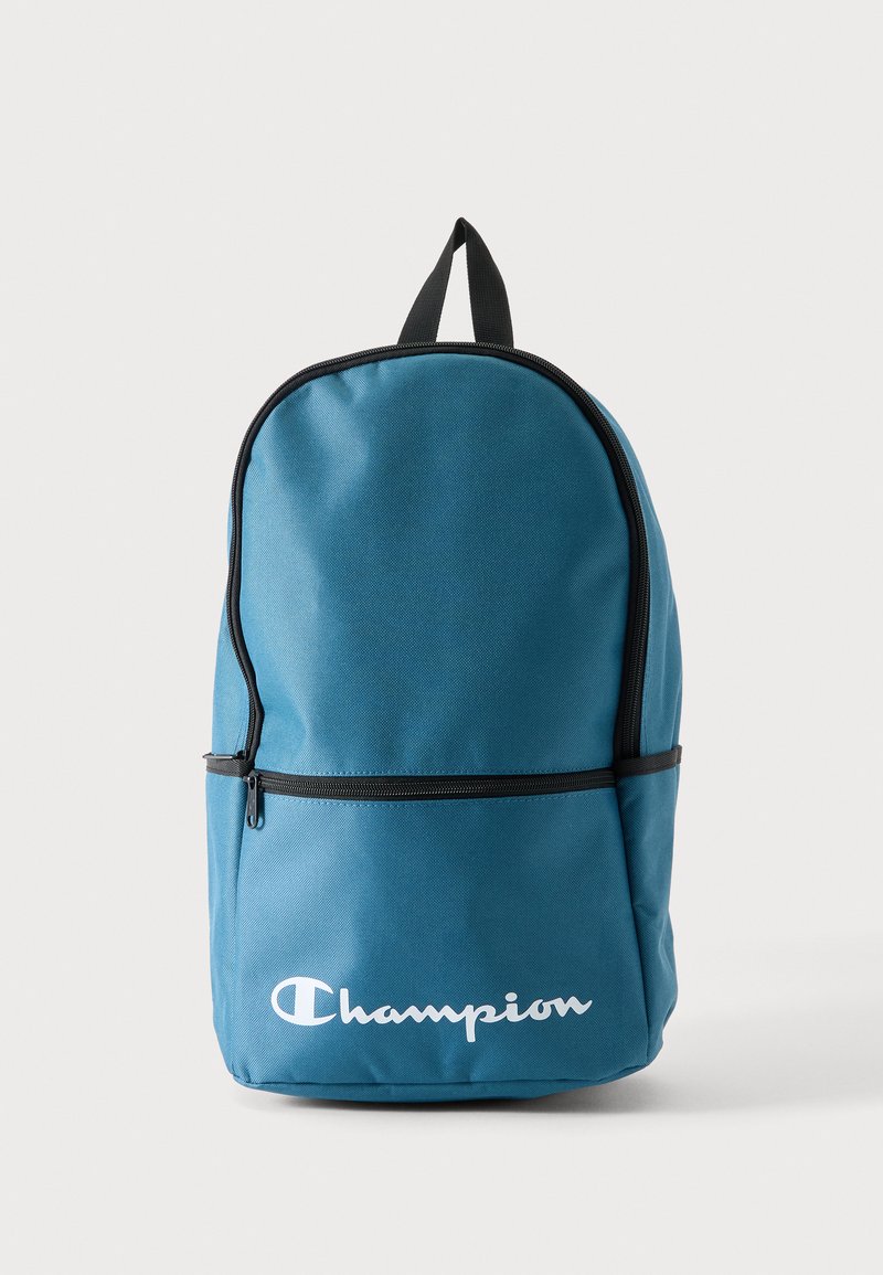 Μπλε σακίδιο Champion με μαύρο φερμουάρ, μπροστινή τσέπη με φερμουάρ και επάνω λουράκι για κράτημα σε λευκό φόντο.