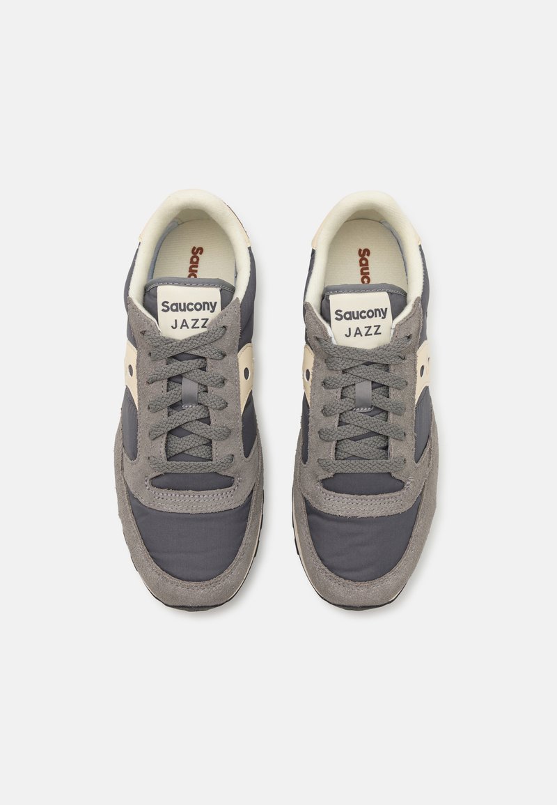 Sneakers Saucony Jazz in grigio e beige, con una tomaia in mesh e suede, collare imbottito, chiusura con lacci e etichetta con logo sulla linguetta.