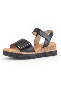 Sandale en cuir noir avec une semelle en liège. Comprend une sangle réglable et un détail de boucle bien en vue. Texture lisse et design ouvert.