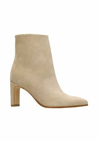 Beige suède enkellaarsje met een spitse neus en een gestapelde hak. Een gladde textuur en minimale details zorgen voor een strakke uitstraling.