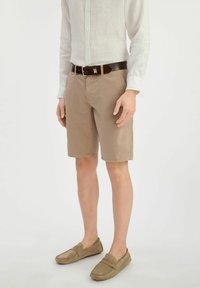 Khaki szorty z zamek błyskawicznym, przednimi kieszeniami i klasycznym krojem. Połączone z jasnym lnianym koszulem i zamszowymi mokasynami.