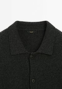 Dark gray knitted cardigan with a classic collar, featuring vertical ribbing, five black buttons, and a label at the neckline.